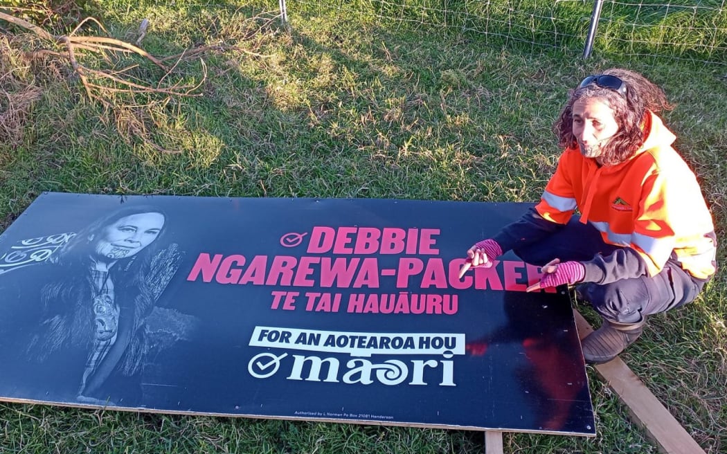 Tuhi-ao Bailey Parihaka with a damaged Te Pāti Māori billboard.