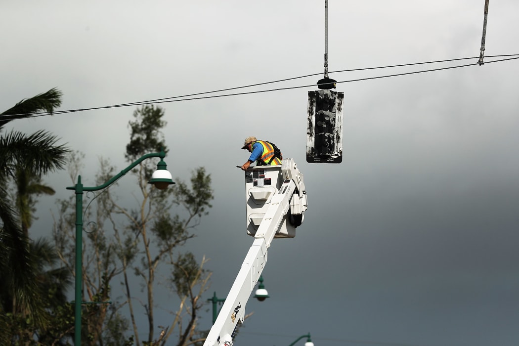 An electrical worker repairs traffic lights in Naples, Florida after Hurricane Irma swept through on 11 September, 2017.