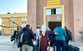 People fleeing from the Gaza Strip queue up in the Egyptian part of the Rafah border crossing with the Palestinian enclave, on December 3, 2023, amid continuing battles between Israel and the militant group Hamas.