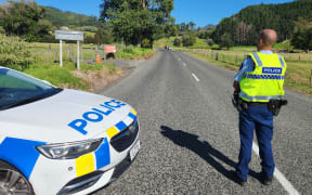 A police officer stands at the roadblock on 309 Road in Waiau, Coromandel following a shooting incident which has left one dead.