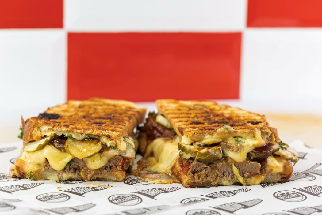 A toasted sandwich with meatloaf and cheese.