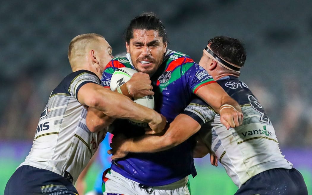 Warriors forward Tohu Harris tries to break through two North Queensland tacklers.