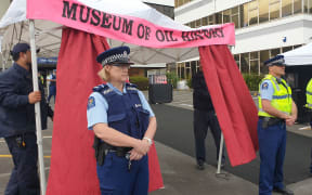 Police stand guard as OMV security dismantles the protesters' construction at the oil company's offices in New Plymouth.