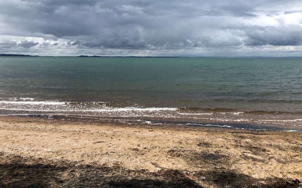 beach with calm sea and dark grey clouds