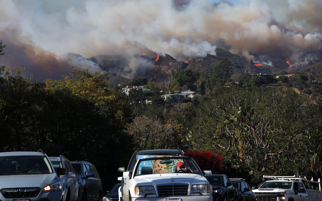 PACIFIC PALISADES, CALIFORNIA - JANUARY 07: People drive out of harm’s way as the Palisades Fire burns amid a powerful windstorm on January 7, 2025 in Pacific Palisades, California. The fast-moving wildfire is threatening homes in the coastal neighborhood amid intense Santa Ana Winds and dry conditions in Southern California.   Mario Tama/Getty Images/AFP (Photo by MARIO TAMA / GETTY IMAGES NORTH AMERICA / Getty Images via AFP)