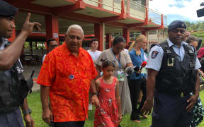 Frank Bainimarama leaves a polling station with his granddaughter