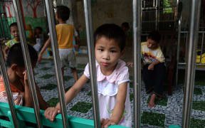 A young girl looks at visitors inside a state-run orphanage on the outskirts of Hanoi, Vietnam in September 2014.