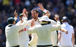 Mitchell Starc of Australia (C) celebrates with teammates after taking the wicket of England's Zak Crawley.