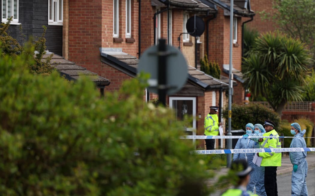 Police forensic officers examine the crime scene in Hainault, east of London on April 30, 2024, where a 36-year-old man wielding a sword was arrested following an attack on members of the public and two police officers. A 13-year-old boy died on Tuesday after five people, including two police officers, were wounded by a man wielding a sword in east London, police said. "It's with great sadness that one of those injured in this incident, a 13-year-old boy, has died from their injuries," Chief Superintendent Stuart Bell, from the Metropolitan Police, told reporters. (Photo by Adrian DENNIS / AFP)