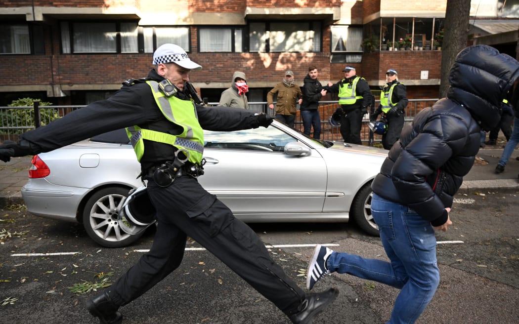 A police officer chases a man through streets close to the 'National March For Palestine' in central London on November 11, 2023, as counter-protest groups are monitored by police close to the route of the main march.
