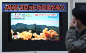 A pedestrian walks in front of a television screen displaying file news footage of a North Korean missile launch, in Tokyo, on Wednesday.