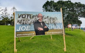 A photo of a billboard from Joe Zhou that is clearly damaged from graffiti.