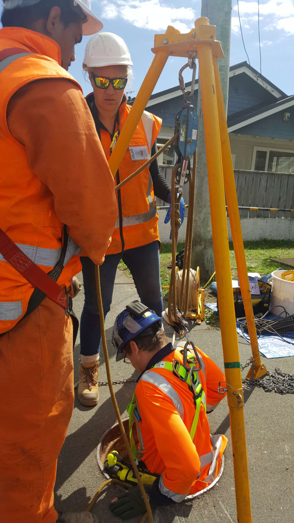 Freshwater ecologist Alex James is lowered through a maintenance hole in the footpath to reach the piped stream below.