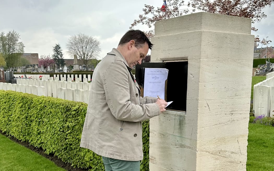 Andrew Mehrtens signing the visitor's book at Bailleul Communal Cemetery Extension