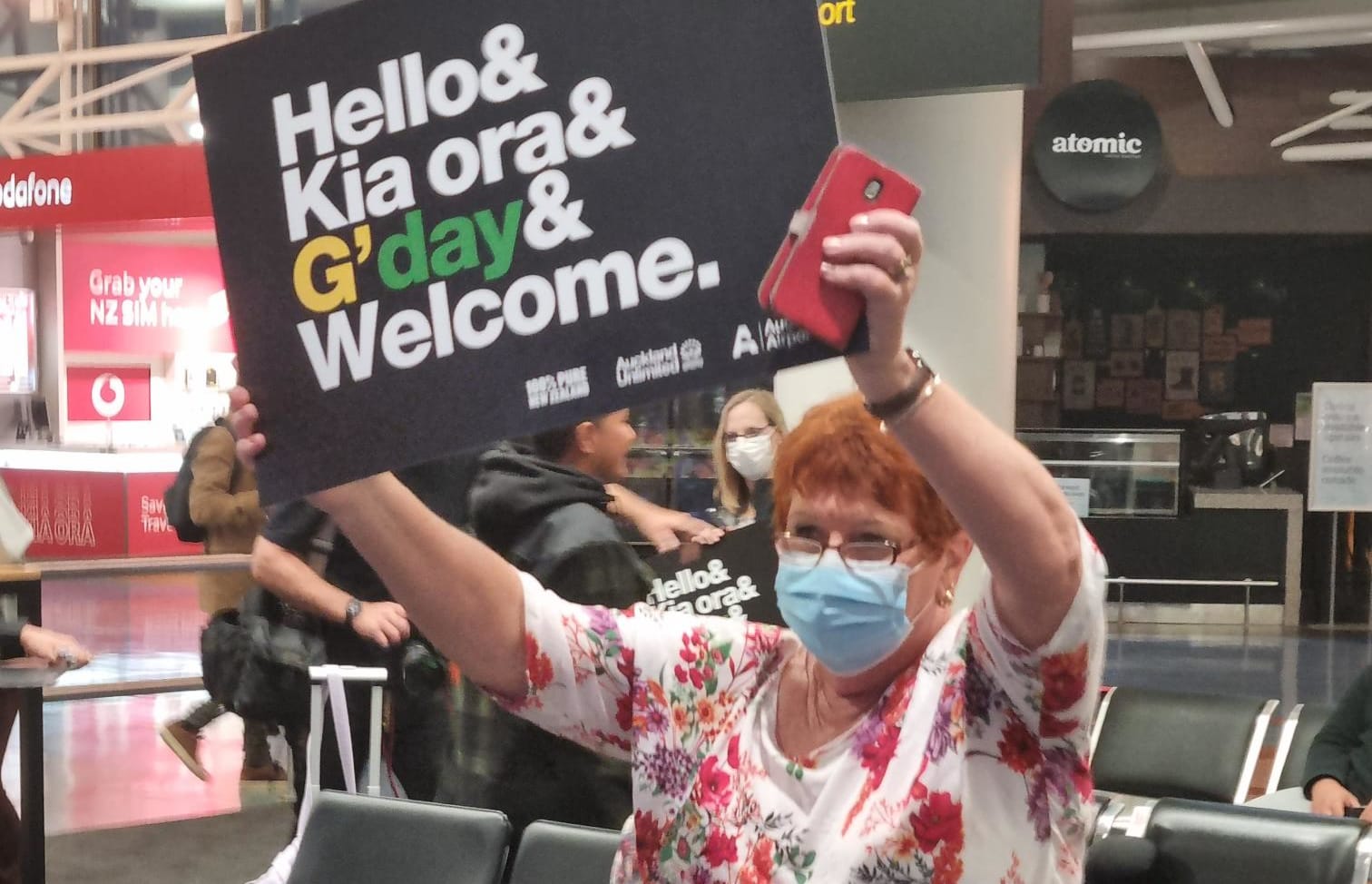 A woman at Auckland Airport holds a welcome sign as flights from Australia are due on the first day that the border has reopened to Australians without a requirement for isolation.