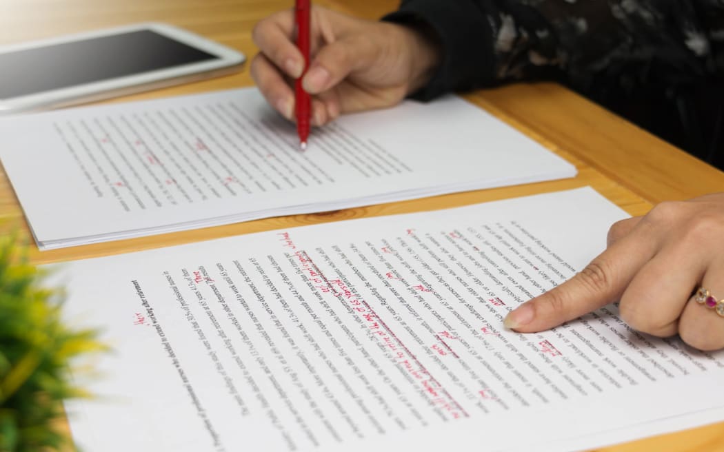 hand working on paper for proofreading. marking paper. grading paper.