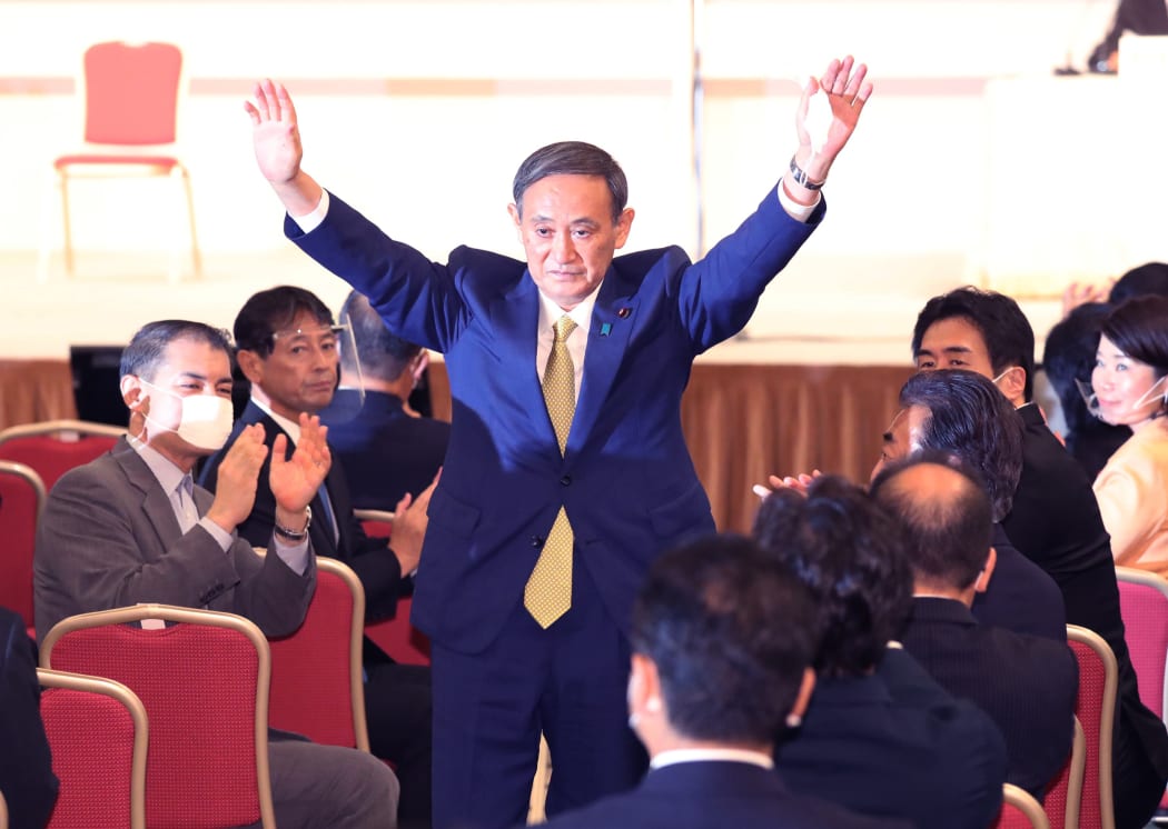 Japan's Chief Cabinet Secretary Yoshihide Suga waves his hands after winning in the LDP presidential election