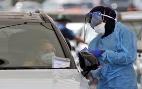 A health worker conducts a PCR test at St Vincent's Bondi Beach Covid-19 drive through testing clinic, Sydney, 22 December 2021.