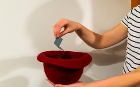 Woman's hand drawing a card with a name from hat. (File picture)