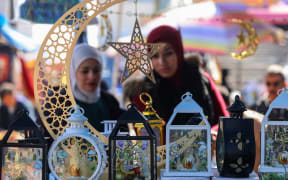 Iraqi women check traditional lanterns known in Arabic as "Fanous Ramadan " at the Shorja market in central Baghdad on February 27, 2025, as Muslim worshippers prepare to welcome the holy fasting month of Ramadan. (Photo by AHMAD AL-RUBAYE / AFP)