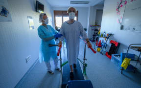 A physiotherapist helps a patient in rehabilitation as he recovers from Covid-19, at a hospital in eastern France, on 14 April, 2020.