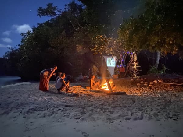 The Powles family enjoy a bonfire and watch a movie screened on a sheet hung from the trees.
