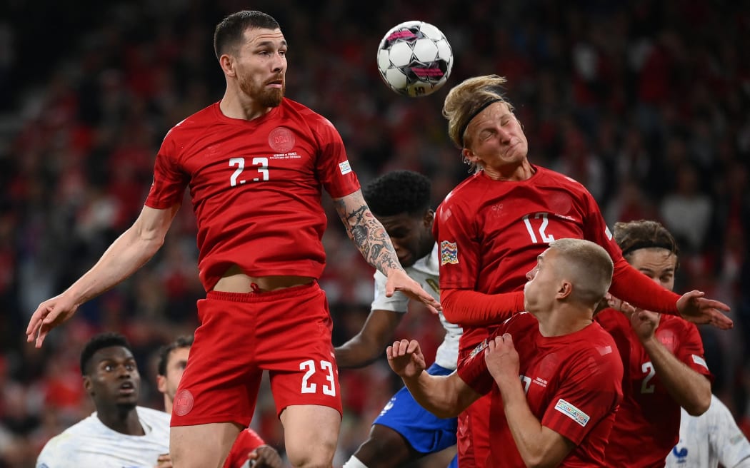 (FILES) In this file photo taken on September 25, 2022 Denmark's midfielder Pierre-Emile Hojbjerg (L) and Denmark's forward Kasper Dolberg both jump to head the ball during the UEFA Nations League football match between Denmark and France in Copenhagen on September 25, 2022. - Danish sporting goods brand Hummel will tone down its logo on Denmark's football jerseys at the 2022 World Cup in Qatar to protest against the emirate's human rights record, it said on September 28, 2022. (Photo by FRANCK FIFE / AFP)