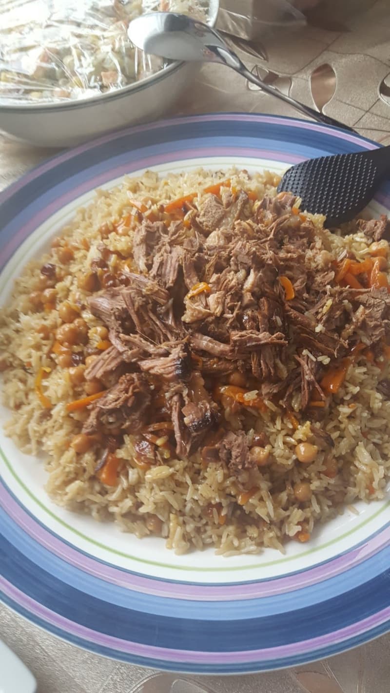 A plate filled with rice and topped with carrots and meat chunks.