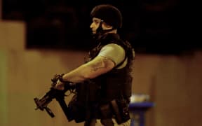 An armed police officer walks at the scene in the Melbourne bayside suburb of Brighton during the siege.