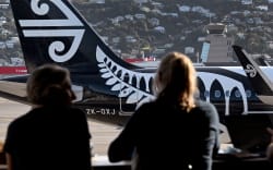A photo taken on June 27, 2022 shows passengers looking at an Air New Zealand planes as they wait for their flight at Wellington Airport. (Photo by William WEST / AFP)