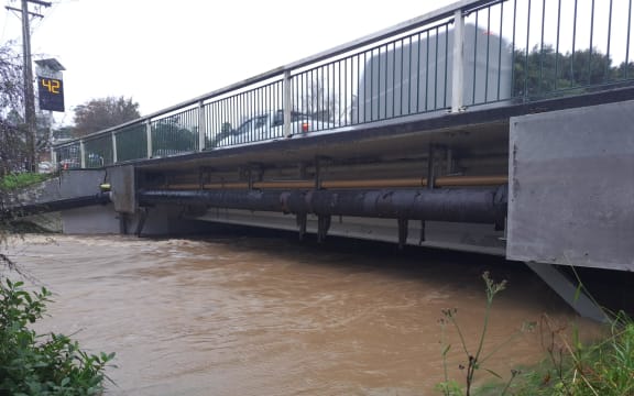 Don Buck Road bridge overflowing in West Auckland.