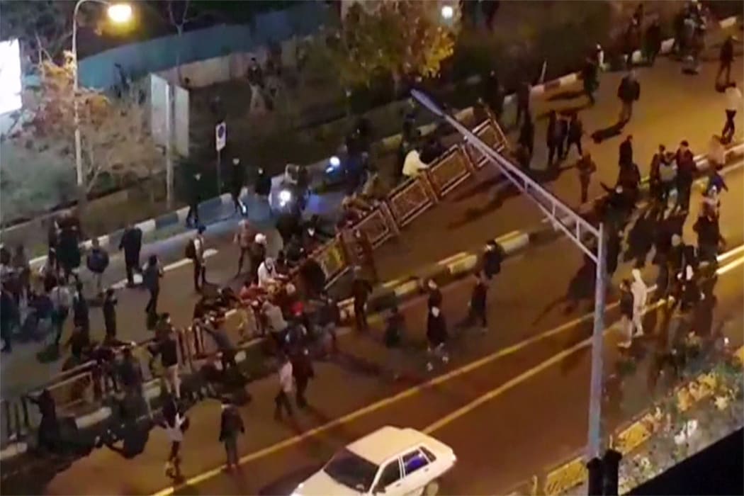 Men pull at a fence in a street in Tehran on Saturday, in a video released by Iran's Mehr News agency.