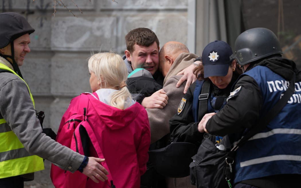 Two men comfort each other as Ukrainian police psychologists provide assistance to local residents following a missile attack in Sumy, northeastern Ukraine, on April 13, 2025, amid the Russian invasion of Ukraine. A Russian ballistic missile attack on Ukraine's northeastern city of Sumy killed at least 31 people and wounded 84 on Palm Sunday, Kyiv said, in another deadly attack on civilians that came after a top US official travelled to Russia. (Photo by Oleg VORONENKO / AFP)