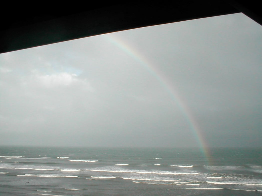 rainbow in grey clouds over sea