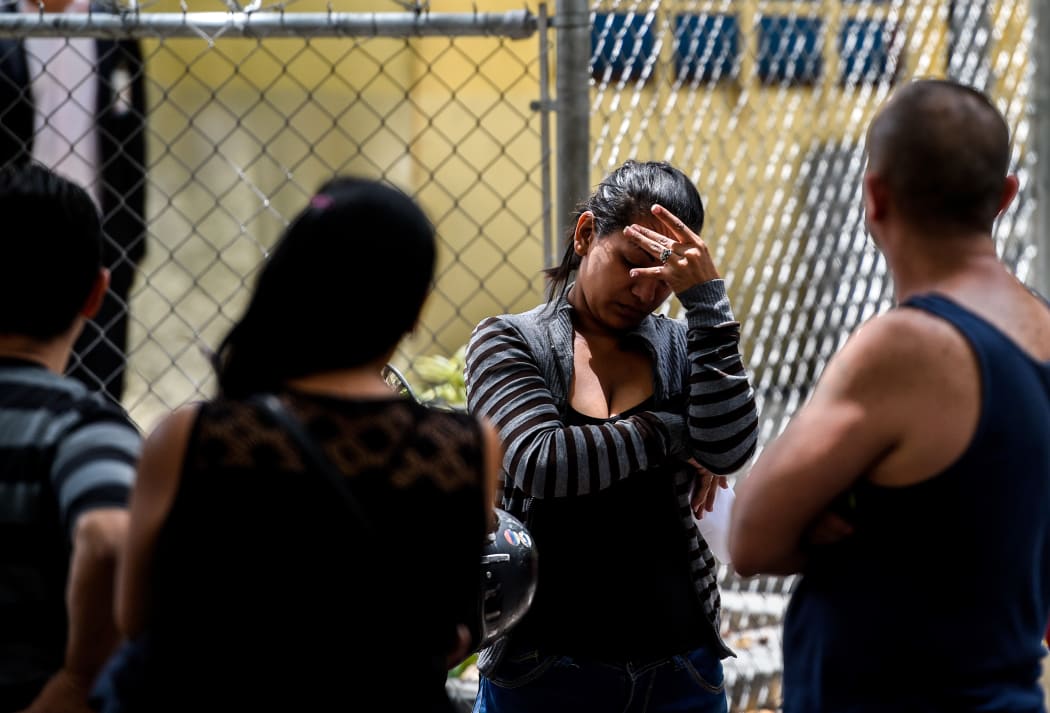A relative of one of the victims of the night club where a tear gas grenade was detonated waits outside the morgue in Caracas.