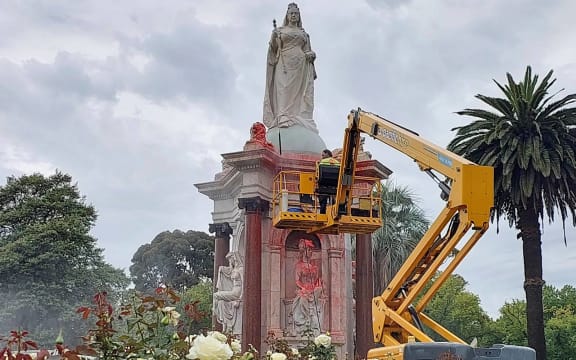 A council worker cleans the statue to Britain's Queen Victoria that was defaced in the Royal Botanic Gardens Victoria in Melbourne on January 25, 2024, ahead of Australia Day. (Photo by Martin PARRY / AFP)