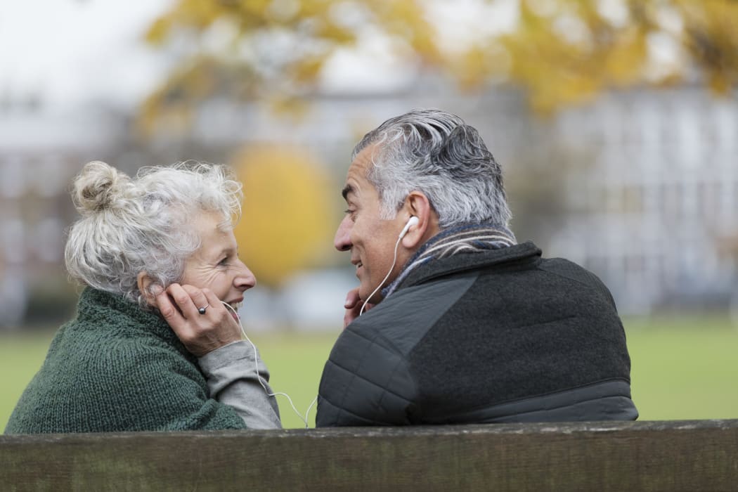 Happy senior couple sharing headphones, listening to music in park. (Photo by Tom Merton/CAIA IMAGE/CAIA IMAGE / NEW / Science Photo Library via AFP)