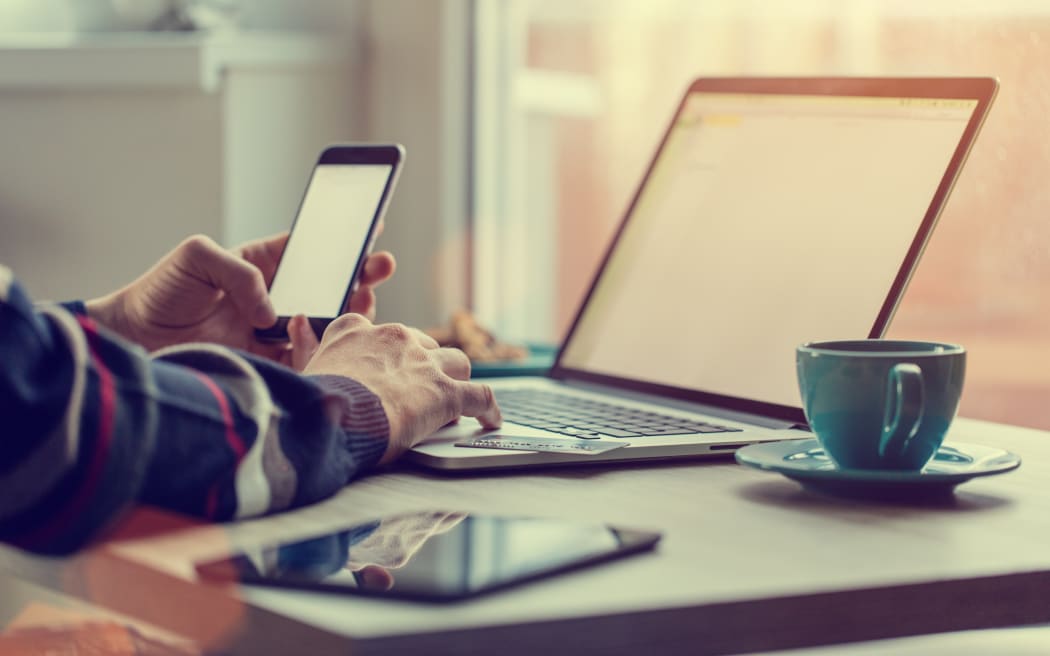 Man working on notebook, with a fresh cup of tea or coffee. Home work concept.