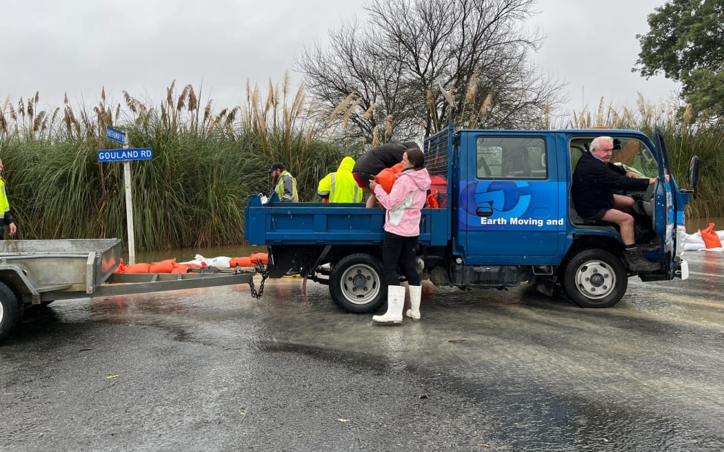 Residents and contractors build a sandbag wall on the corner of Hathaway and Gouland streets to stop surface water on a paddock pouring onto the street.