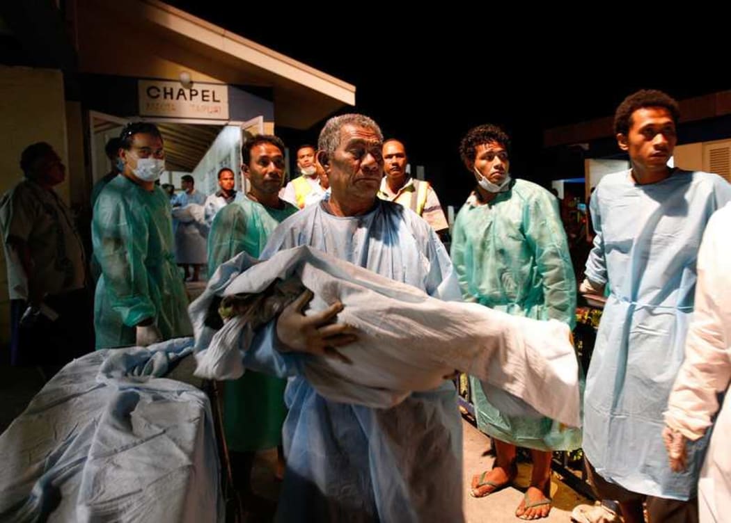 A grandfather carries his child to a hearse at Moto'otua Hospital following the tsunami of 2009.
