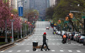 NEW YORK, USA - APRIL 12: An amazon delivery person, with a face mask, crosses a street on Park Avenue, remaining nearly empty due to coronavirus (COVID-19) pandemic in New York City, United States, on April 12, 2020. Tayfun Coskun / Anadolu Agency