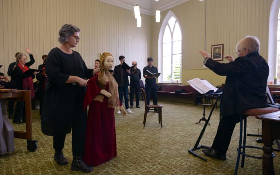 Voices NZ choir in rehearsal for their concert When Light Breaks. There is an almost life-sized puppet.