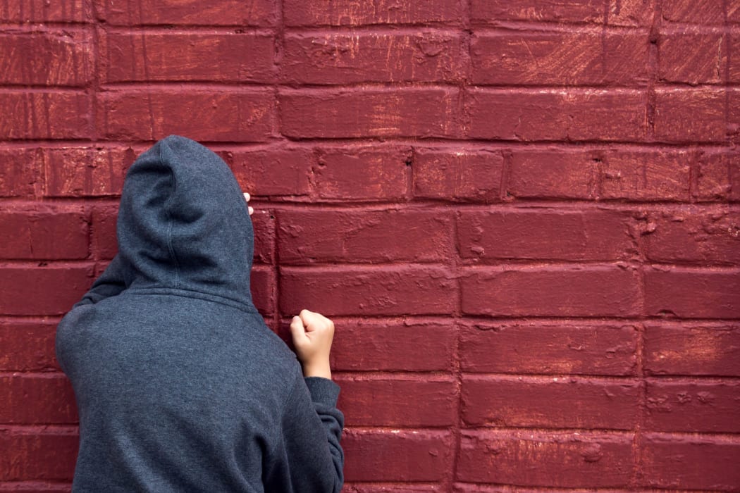 Worried depressed sad teen boy (child) crying near brick wall