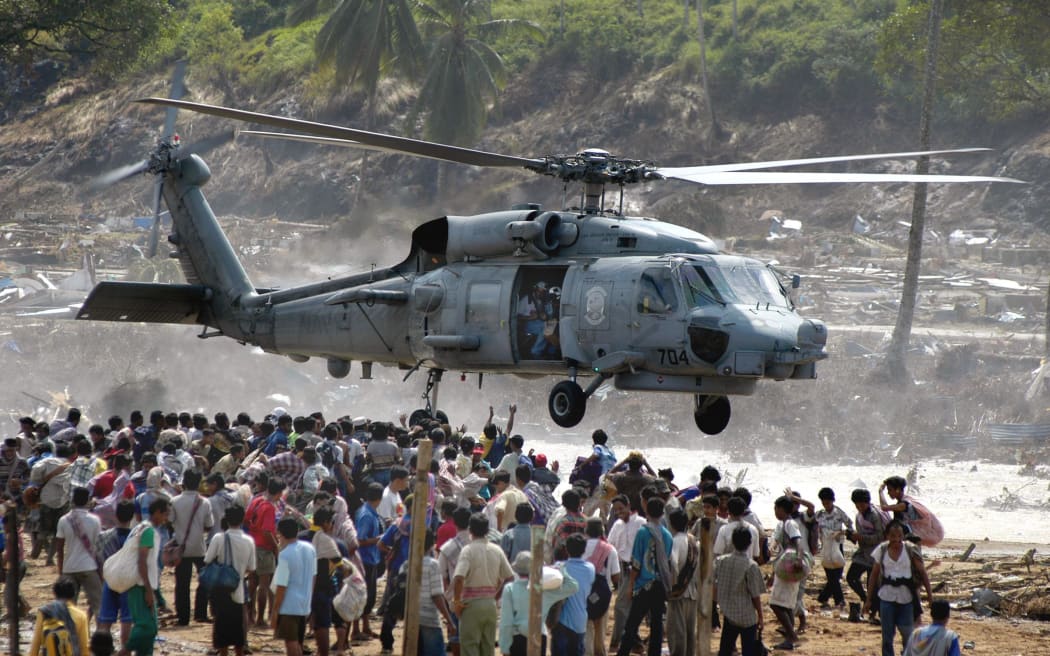 Hundreds of residents of Calang town flock under a US helicopter as volunteers distribute food in Aceh Jaya, in the tsunami-ravaged western Aceh coast, 04 January 2005.