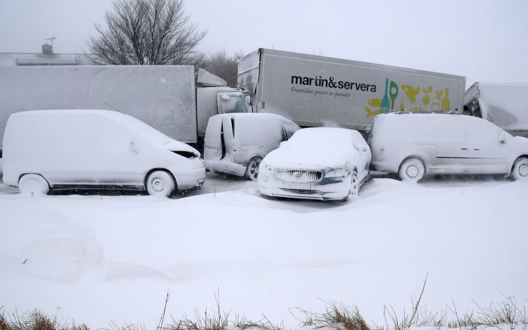 Several trucks and cars, covered with snow, stand deserted after a pileup on February 27, 2018 near Sjobo, southern Sweden.