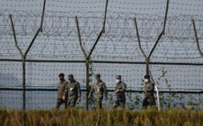 South Korean soldiers walk along a fence of the Demilitarized Zone (DMZ) separating North and South Korea, on the South Korean island of Gyodong on October 6, 2020. (Photo by Ed JONES / AFP)