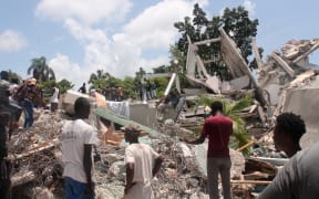 People search through the rubble of what used to be the Manguier Hotel after the earthquake hit on 14 August 
 2021 in Les Cayes, southwest Haiti.