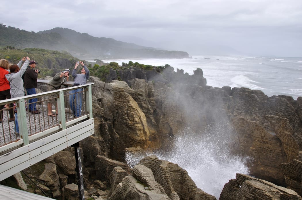 PUNAKAIKI, NEW ZEALAND, MAY 5, 2010: Tourists photograph themselves while the main blowhole is in action at the Pancake Rocks, Punakaiki, West Coast, South Island, New Zealand
