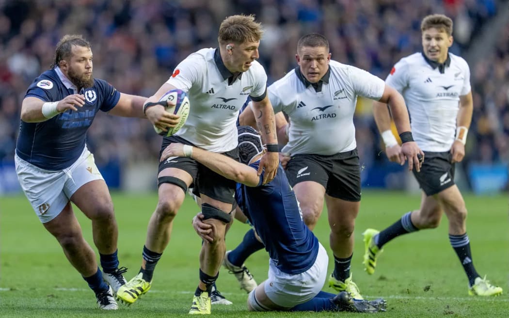 Fabian Holland looks to offload the ball whilst under pressure during the Scotland v All Blacks match.