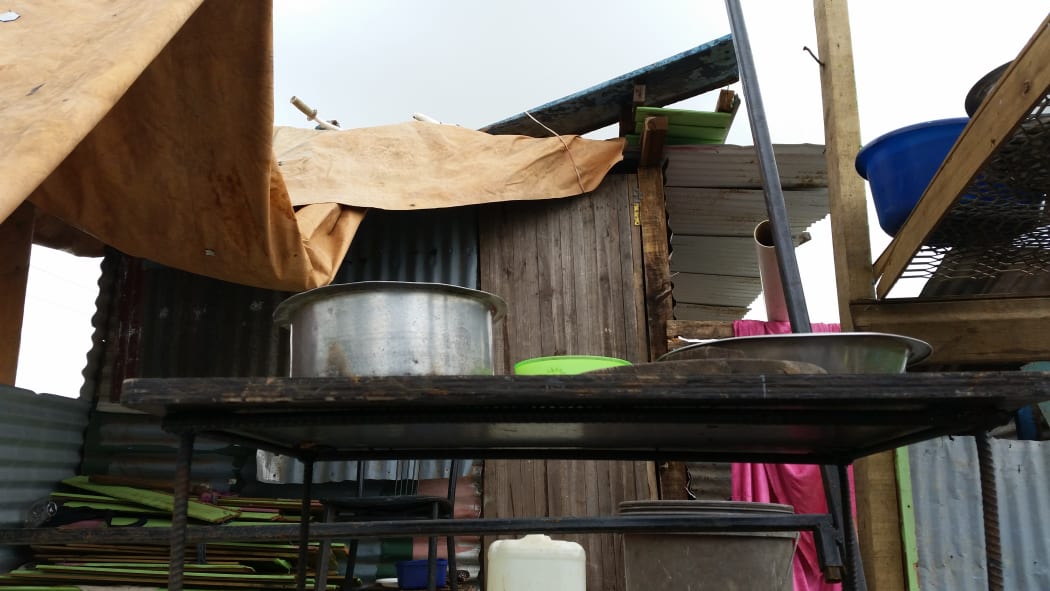 Tarpaulins draped over timbers supports and cooking pots in the open